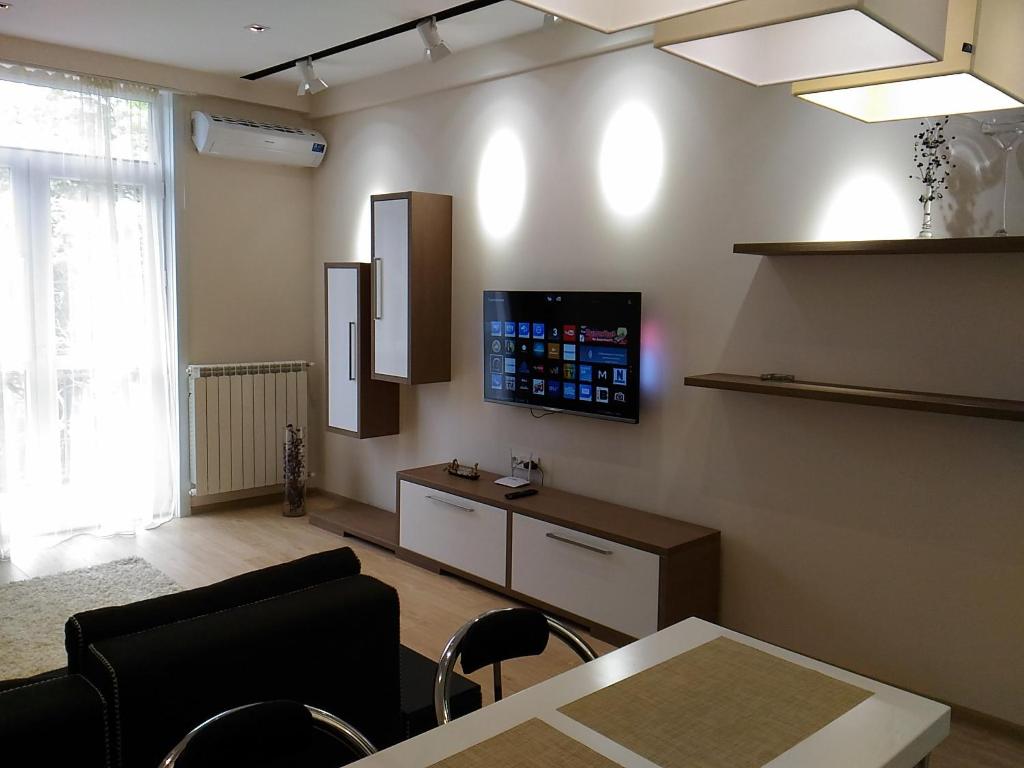 a living room with a table and a tv on the wall at Apartment on Iunkerta Street in Tbilisi City