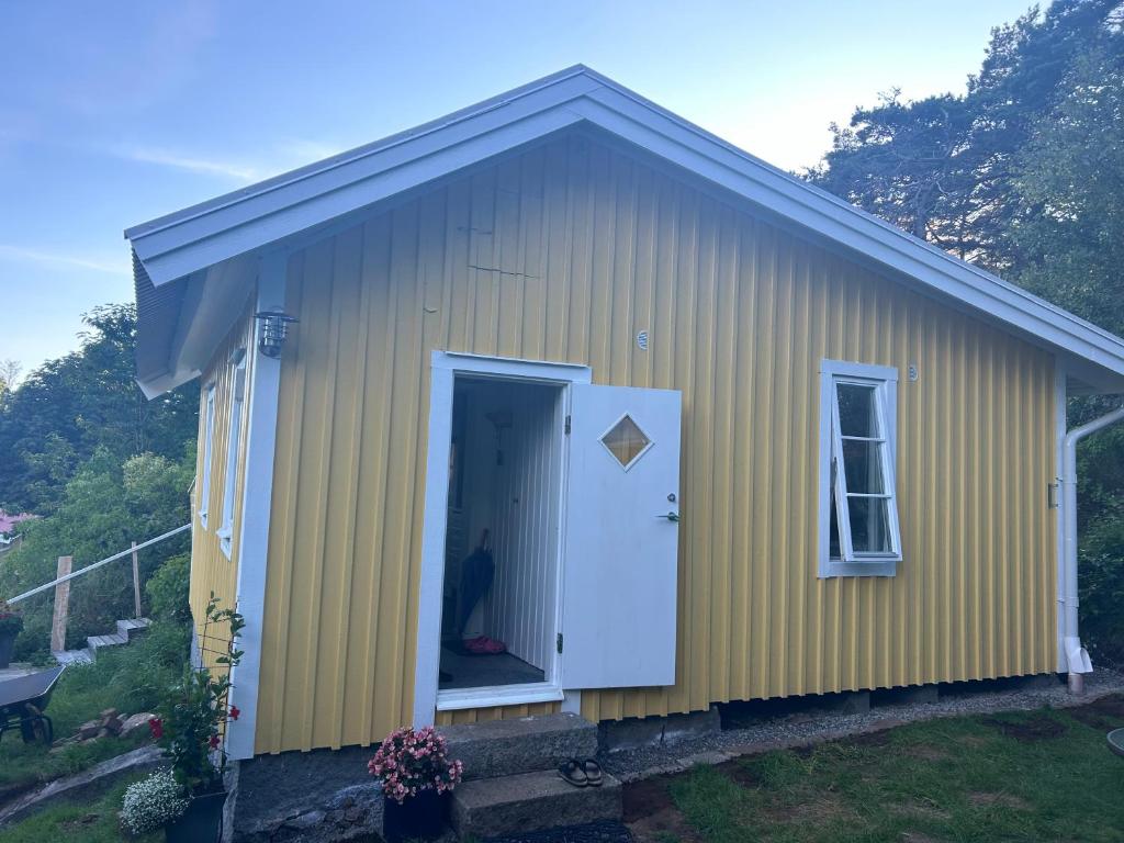 a small yellow building with a white door at Söt stuga in Strömstad