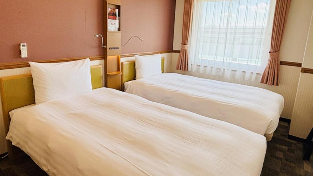 Toyoko Inn Sakudaira-eki Asama-guchi في ساكو: سريرين يجلسان بجانب بعضهما البعض في غرفة