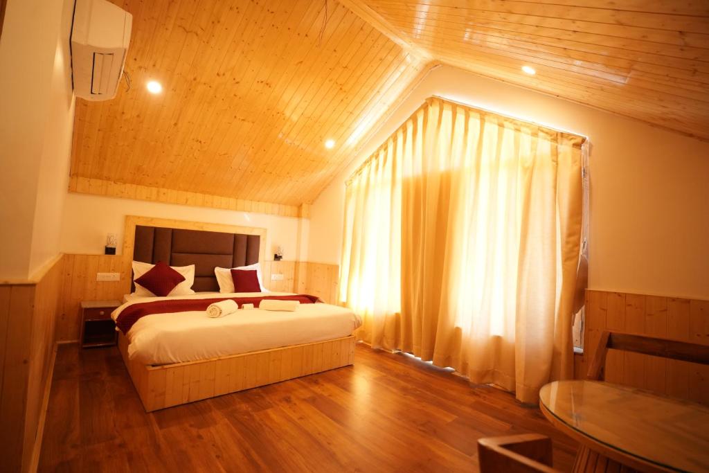 ein Schlafzimmer mit einem Bett und einem großen Fenster in der Unterkunft Wooden Castle Hotel and Resort in Manali