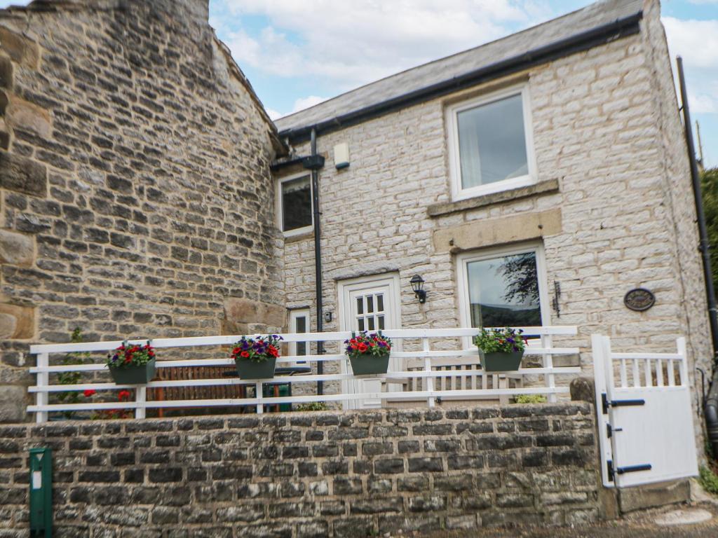 a stone house with potted plants on the stairs at Bank Cottage in Bradwell