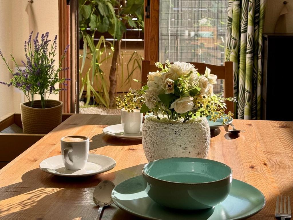 une table en bois avec deux assiettes et un vase avec des fleurs dans l'établissement The Fig Tree Apartment, à Aglantzia