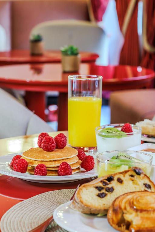 a table with pancakes and berries and a glass of orange juice at Le Cavendish in Cannes