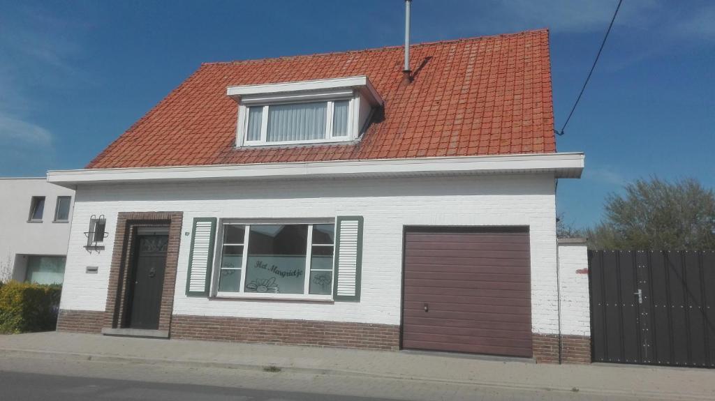 a white house with a red roof and a garage at Het Margrietje in Merkem