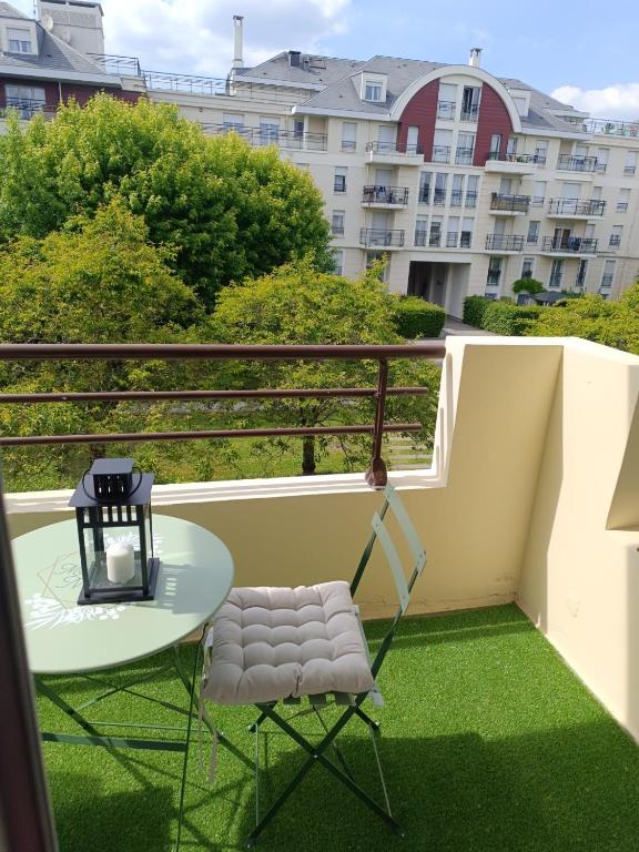 d'une table et d'une chaise sur un balcon avec de l'herbe verte. dans l'établissement Appartement Cosy, 30 minutes de Paris, à Carrières-sous-Poissy
