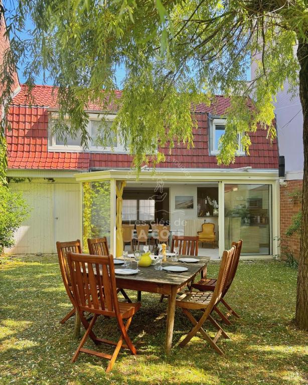 une table et des chaises en bois devant une maison dans l'établissement Maison de famille L'Amandoise, à Le Touquet-Paris-Plage