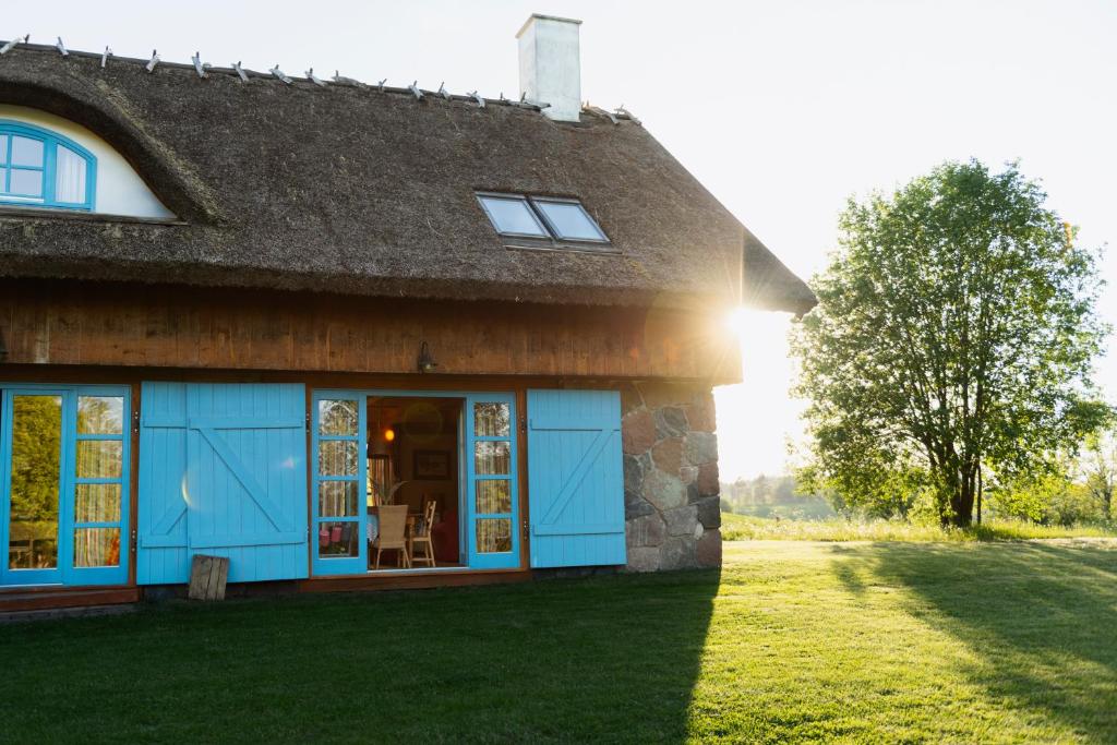 a house with blue doors and a grass yard at Siedlisko Pod Strzechą in Wólka