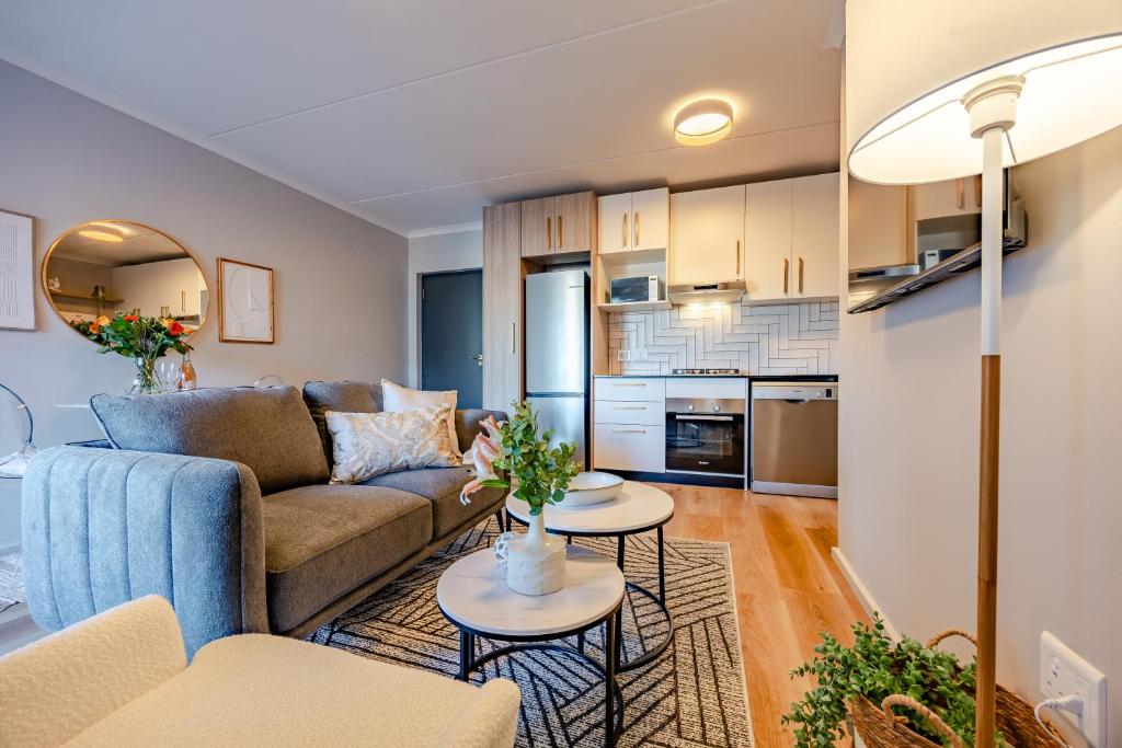 Una sala de estar con un sofá y dos mesas. en Modern 2 bed, 2 bath- Blouberg, en Bloubergstrand