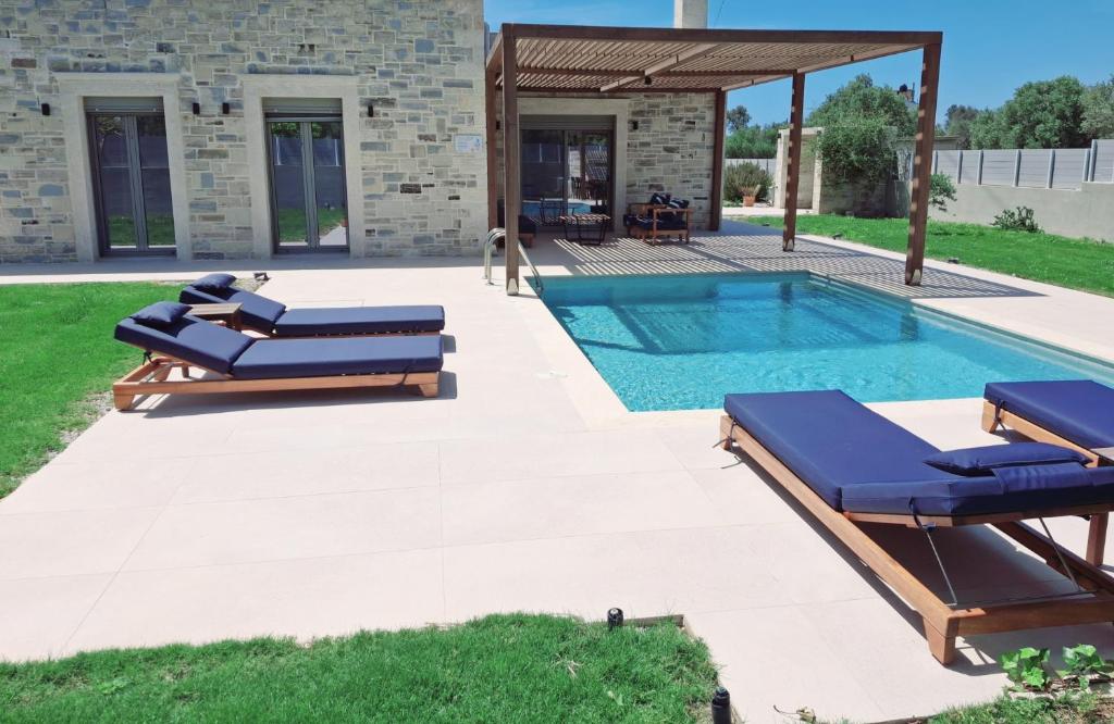 een zwembad met 2 ligstoelen naast een huis bij Marelia Villa 1 in Tympáki