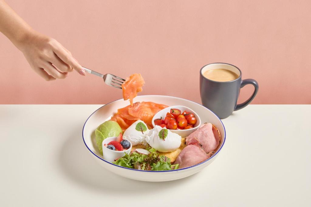 a person eating a bowl of food with a cup of coffee at Days Inn by Wyndham Patong Beach in Patong Beach