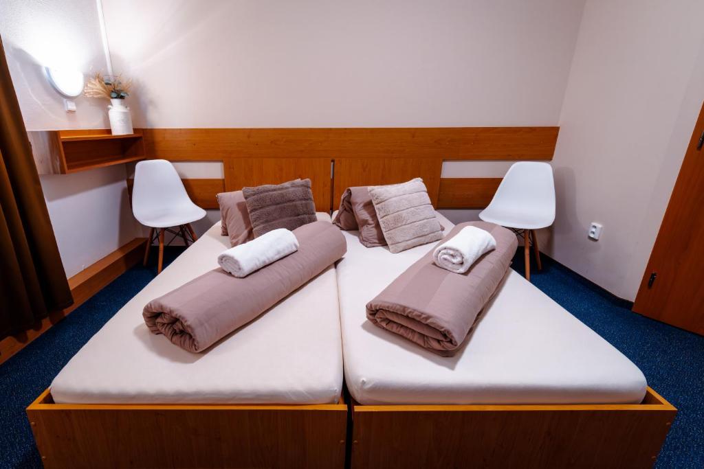two beds in a room with two white chairs at Vinné sklepy Skalák in Skalka