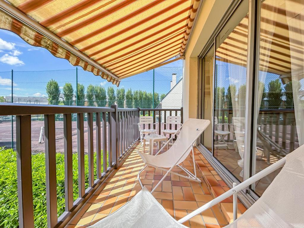 a balcony with white chairs and glass doors at La Pause Cabourgeaise in Cabourg