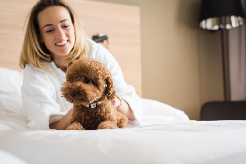 a woman sitting on a bed with a teddy bear at Park Inn by Radisson Vilnius Airport Hotel & Conference Centre in Vilnius