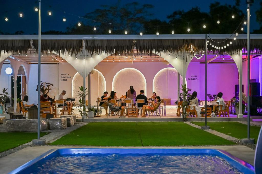 a group of people sitting at tables in a patio at Beach House Pool Villa in Na Jomtien