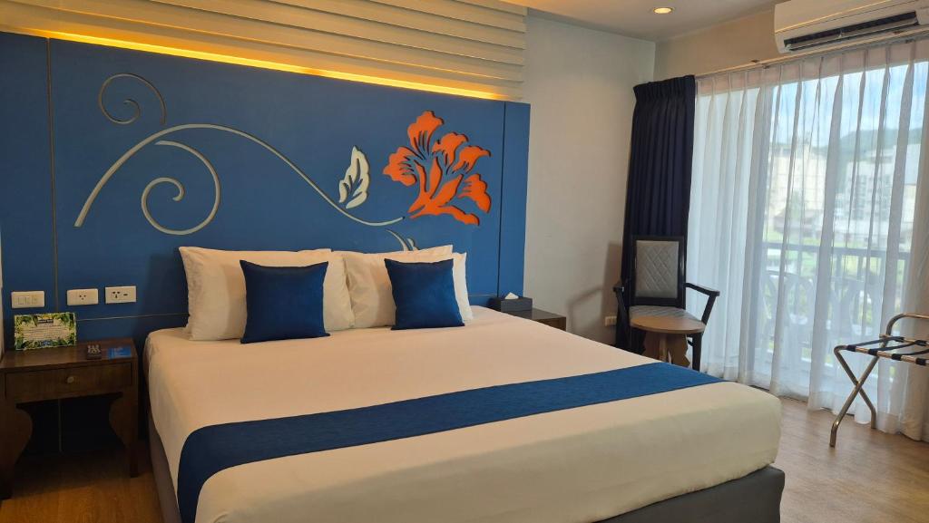 a bedroom with a large bed with a blue wall at Days Inn by Wyndham Patong Beach in Patong Beach