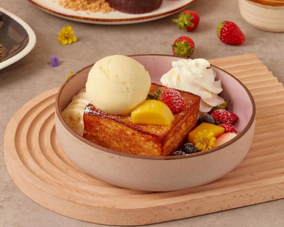 A dessert-style toast bowl topped with ice cream, whipped cream and fresh fruit.