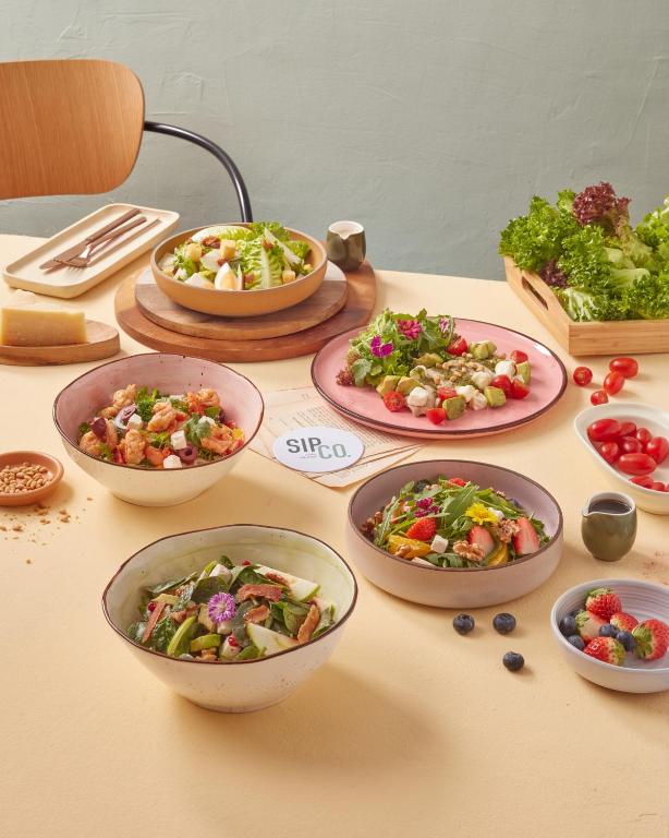 Several colorful salad and fruit dishes are arranged on a dining table.