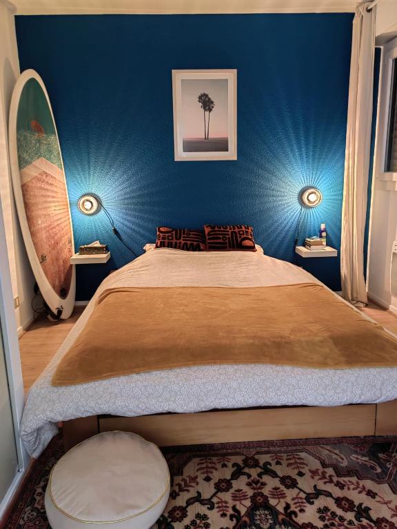 une chambre avec un lit aux murs bleus et une planche de surf dans l'établissement T2 Seignosse Plage - 45M2, à Seignosse