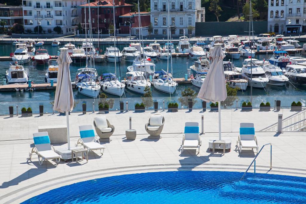 a pool with chairs and boats in a marina at The Grand Tarabya Managed by Accor in Istanbul