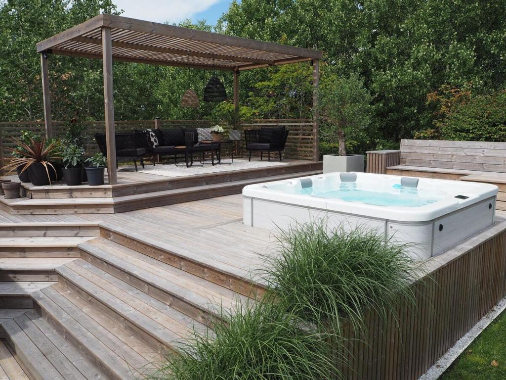 a hot tub on a wooden deck with a gazebo at Social villa near the sea! in Torslanda