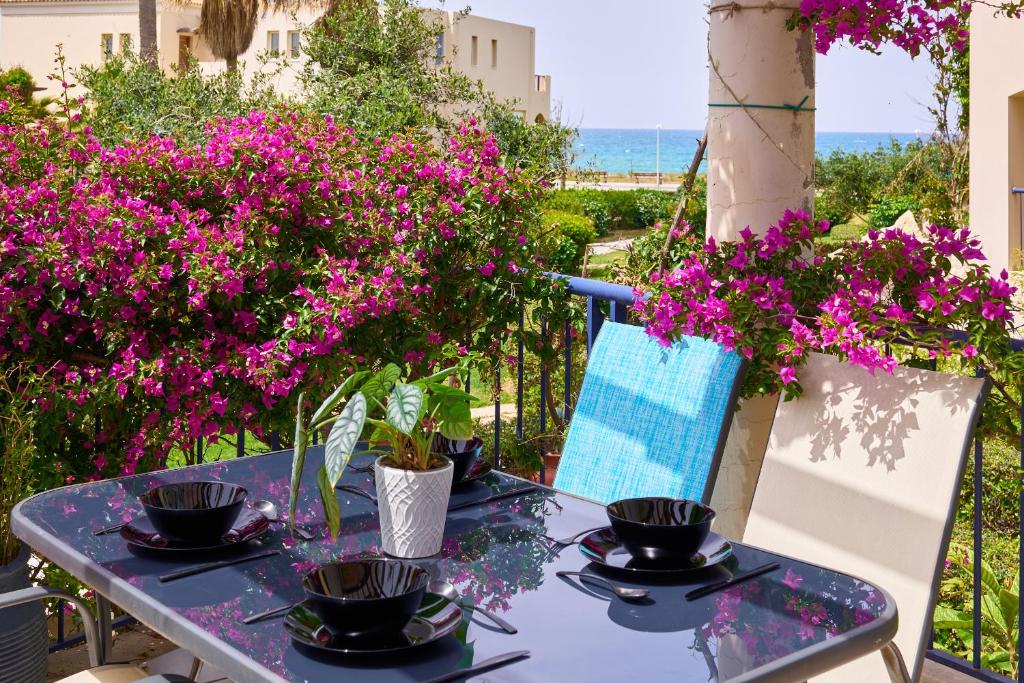 Una mesa azul con flores moradas en un patio. en Elias 1-Bedroom Apartment on the beach with pool, en La Canea