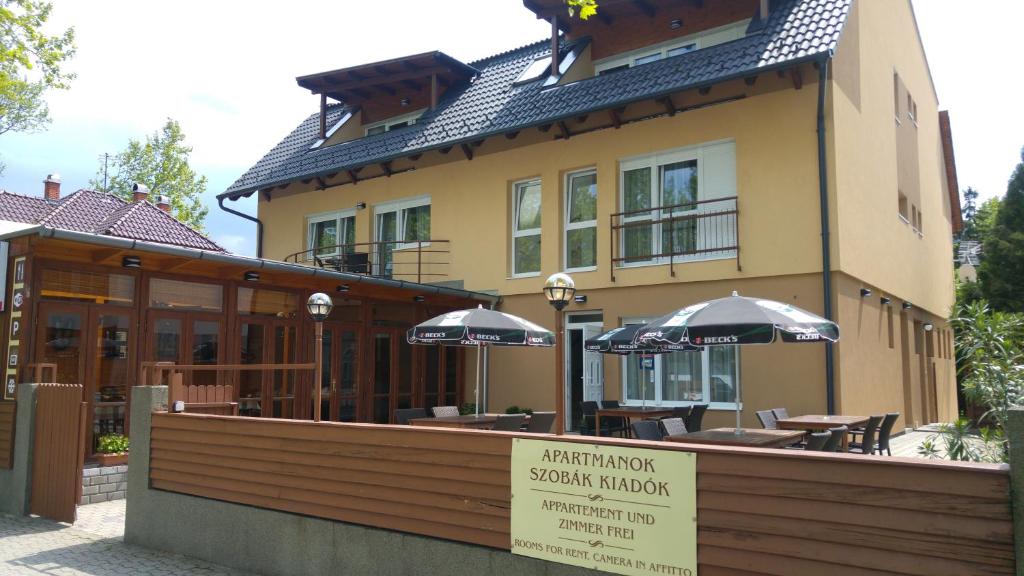 a restaurant with tables and umbrellas in front of a building at Ádám Apartmanház in Siófok