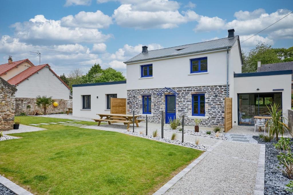 a white house with a picnic bench in the yard at La Maison Valnotte - Proche du port de Carteret in Barneville-Carteret