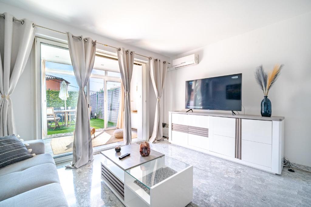 un salon blanc avec une télévision et un canapé dans l'établissement Studio Clim Piscine Nice ouest, à Nice