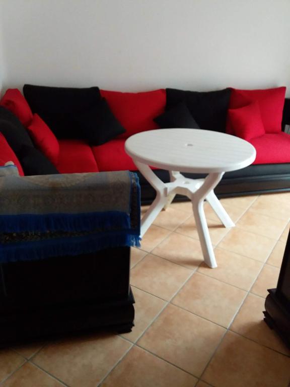 a living room with a white table and a red couch at شوابل in Oued Laou