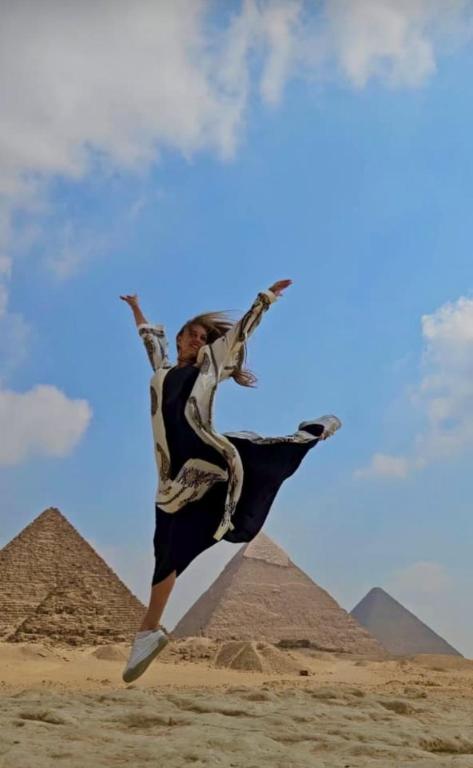 a man jumping in the air in front of the pyramids at Horus pyramids view in Cairo