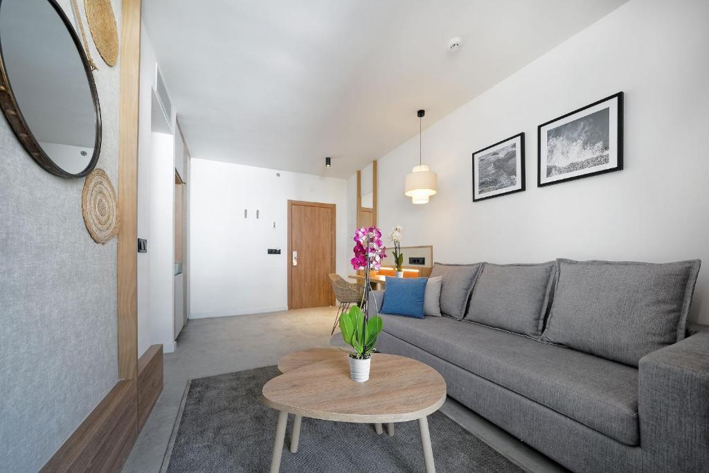 a living room with a gray couch and a table at HOVIMA Suites Costa Adeje in Adeje