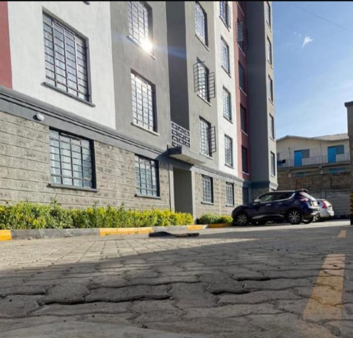 a car parked in front of a large building at Neema Homes Syokimau in Nairobi