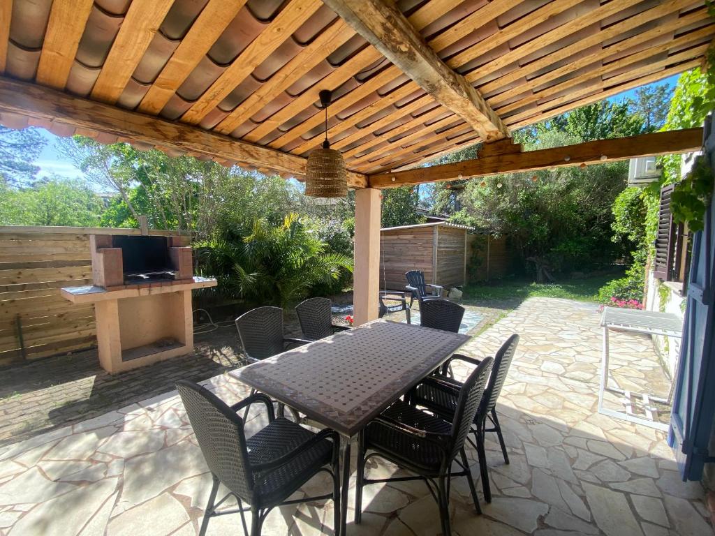 un patio avec une table et des chaises sous une pergola en bois dans l'établissement Résidence Anitrella, à Porto-Vecchio