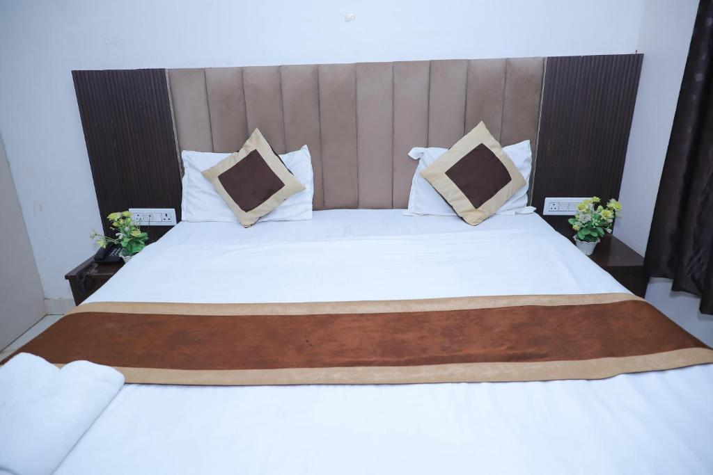 ein großes Bett mit weißen Laken und Kissen in der Unterkunft Hotel Green Apple BAREILLY in Bareilly