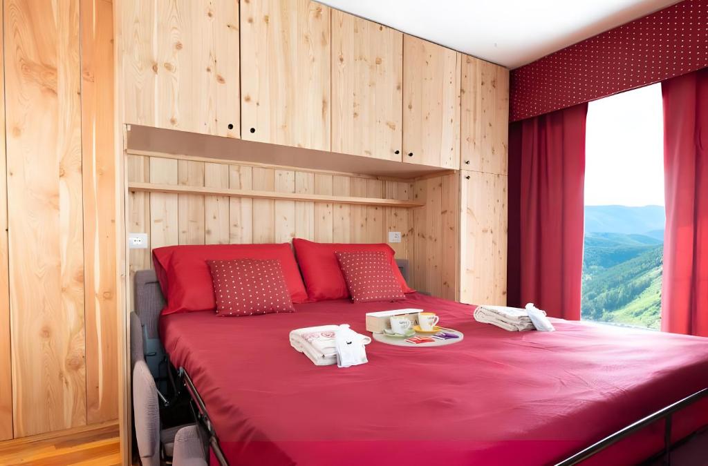 una camera da letto con un letto con lenzuola rosse e una finestra di Maison Cupido a Saint-Rhémy-en-bosses