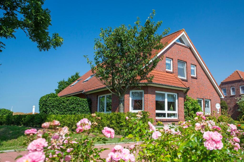 una casa de ladrillo con flores rosas delante de ella en Haus Wiesengrund, en Werdum