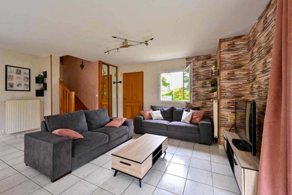 a living room with two couches and a tv at La Maison d'Herbignac - Grand Jardin in Herbignac