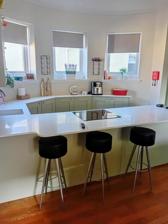 a kitchen with a large white counter and stools at The Bunker, Golf Cottage in Prestwick