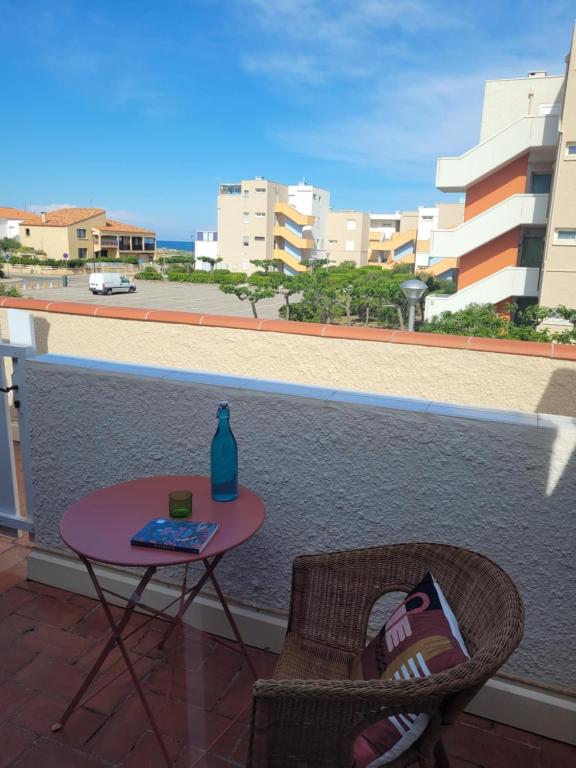 une table et une chaise avec une bouteille sur un balcon dans l'établissement Le studio 29, au Barcarès