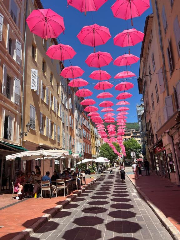une rangée de parasols roses suspendus au-dessus d'une rue dans l'établissement Authentic Old Town Center of Grasse, à Grasse