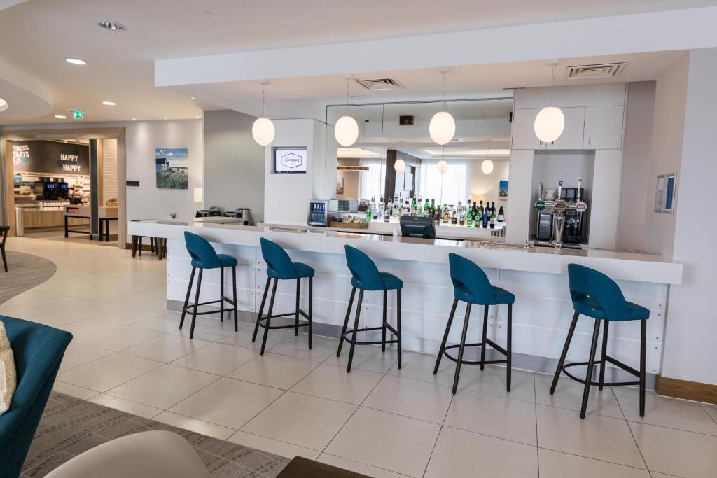a lobby with a bar with blue bar stools at Hampton by Hilton Bournemouth in Bournemouth