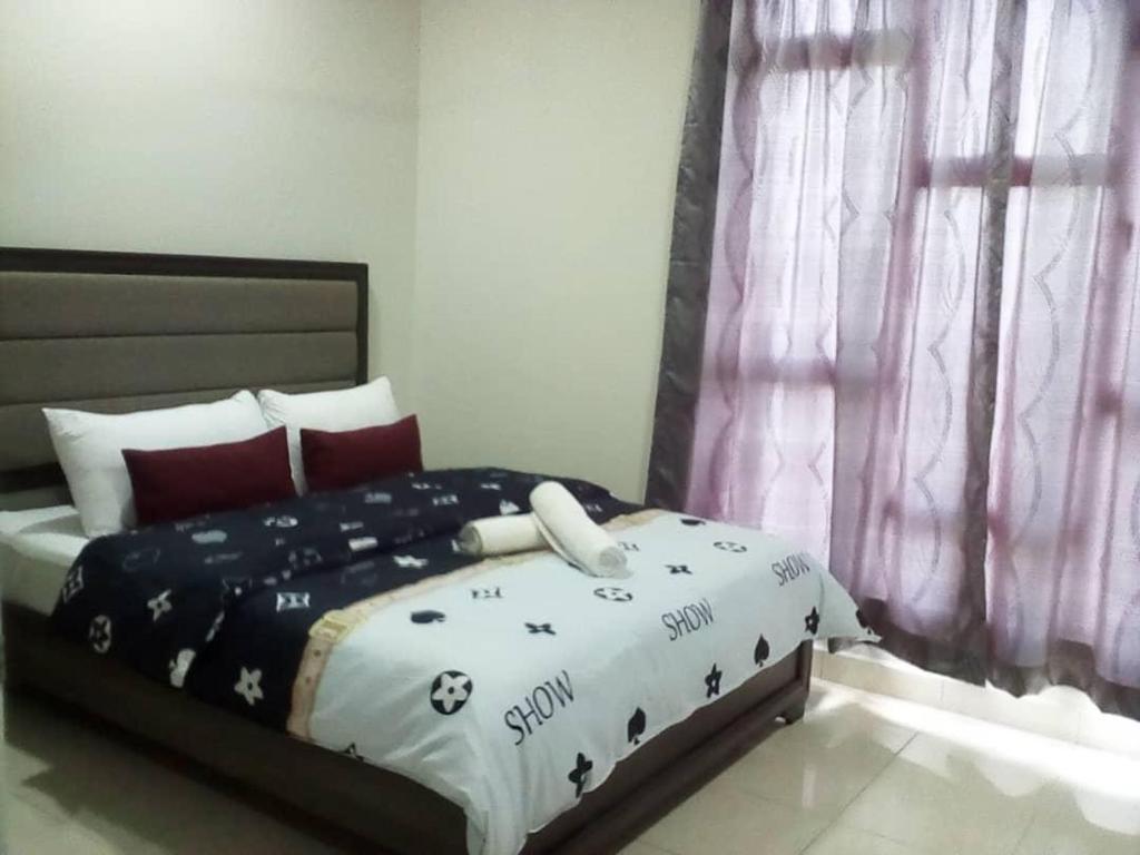 a bedroom with a bed with a black and white comforter at Mstaycation in Melaka