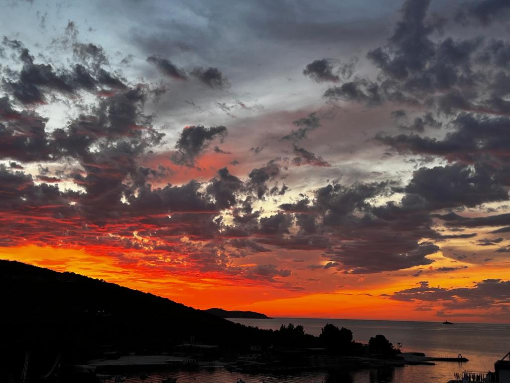 a sunset over a body of water with clouds at Dine Hotel in Ksamil