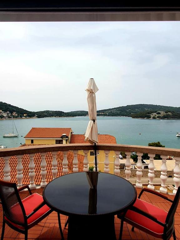 a table and chairs on a balcony with a view of the water at Apartments Perina Tisno in Tisno