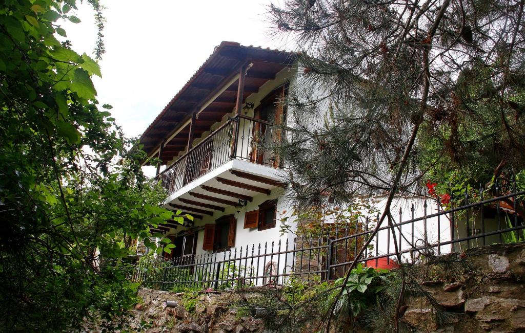 a white building with a balcony in a forest at Katoikia me ta Pitharia in Prinos