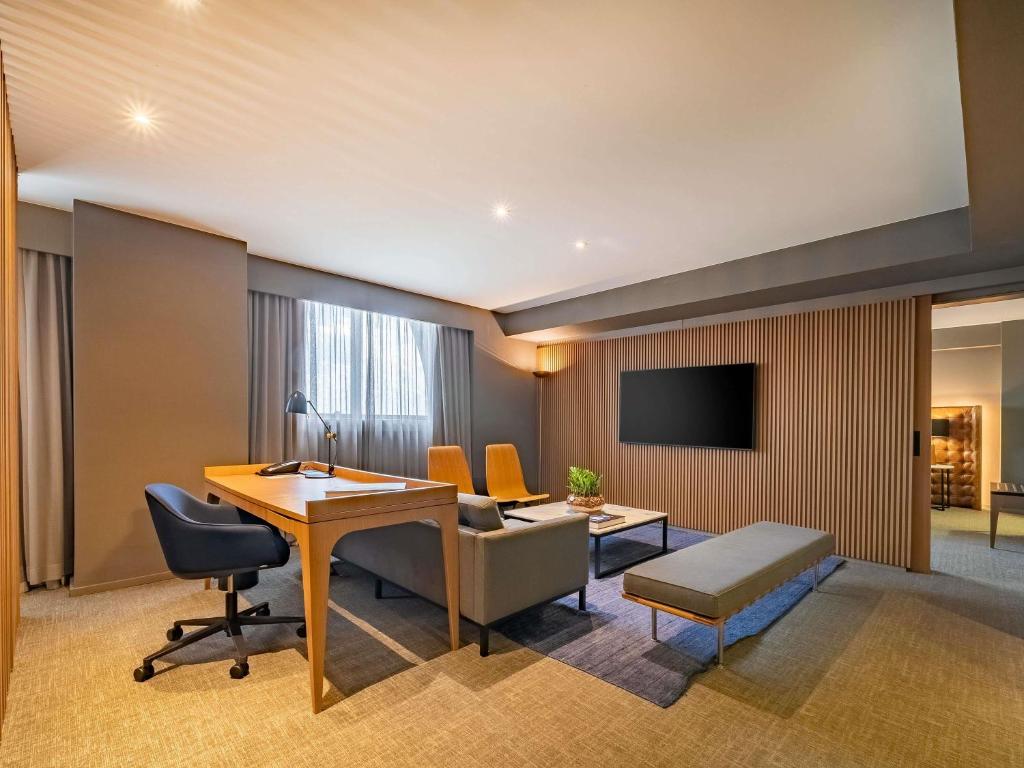 a hotel room with a desk and a tv at Pullman Sao Paulo Guarulhos Airport in Guarulhos