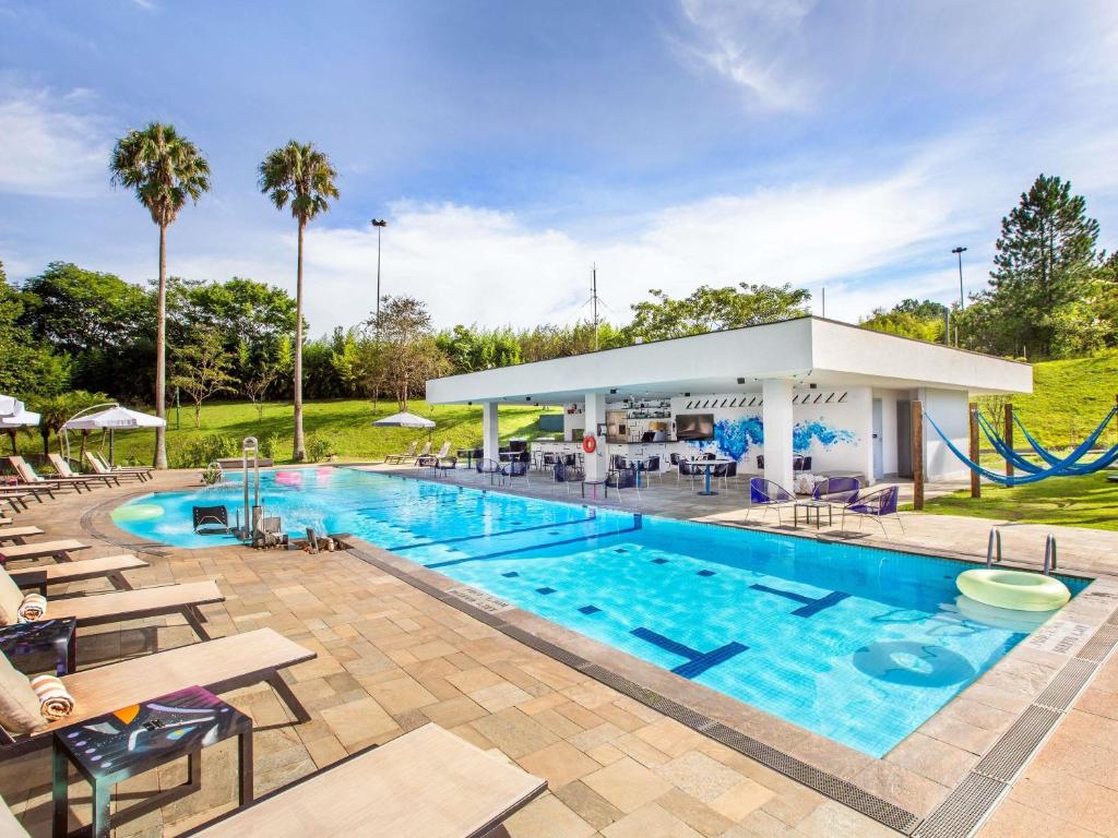 a pool at a resort with chairs and a slide at Pullman Sao Paulo Guarulhos Airport in Guarulhos