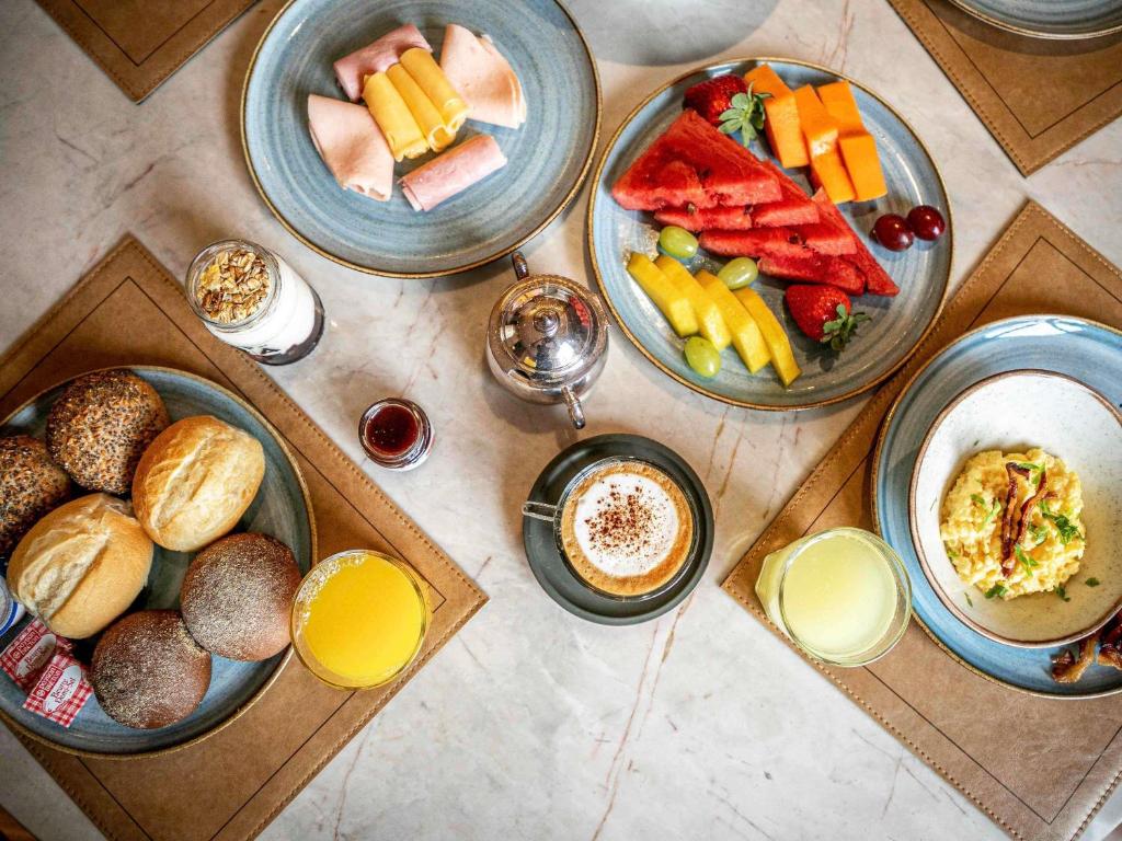 a table with plates of food and bowls of fruit at Pullman Sao Paulo Guarulhos Airport in Guarulhos