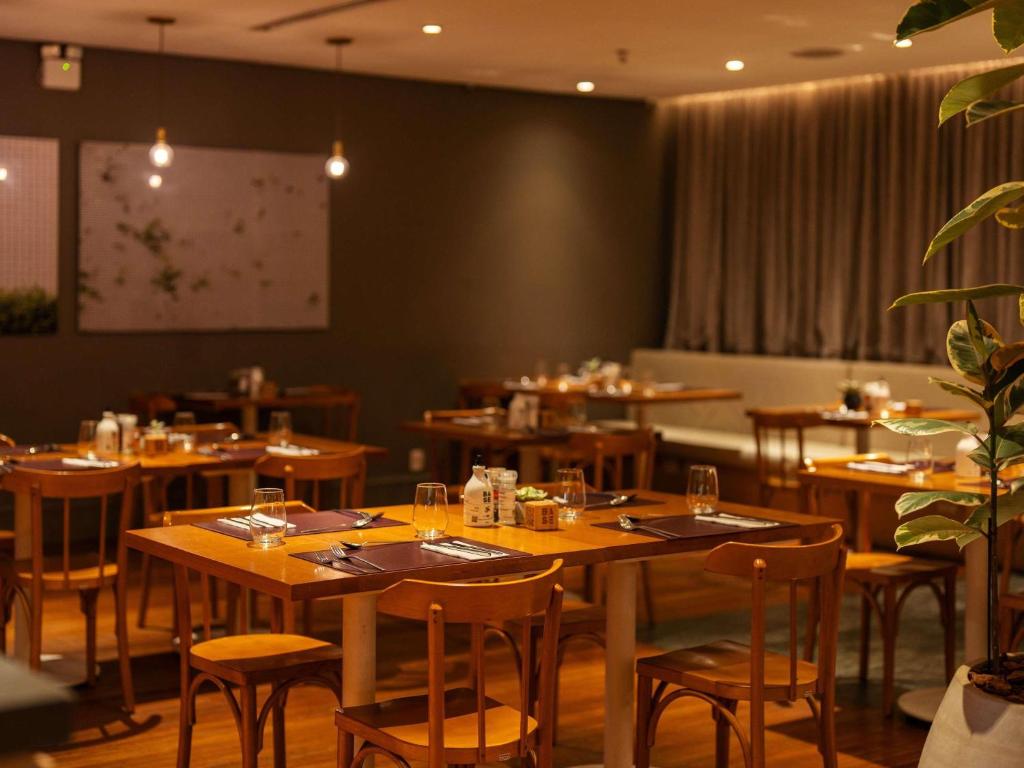 a dining room with wooden tables and chairs at Pullman Sao Paulo Guarulhos Airport in Guarulhos