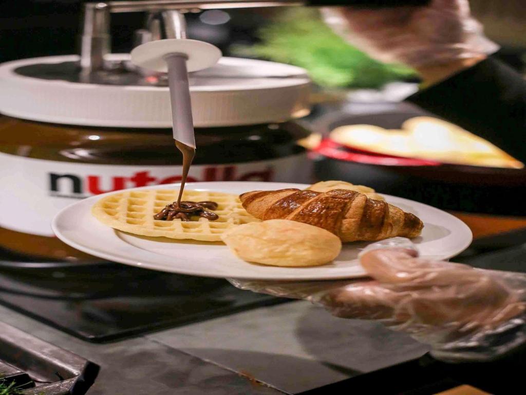 a plate of food with a waffle and a knife at Pullman Sao Paulo Guarulhos Airport in Guarulhos